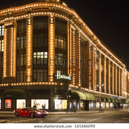 LONDON, UNITED KINGDOM - CIRCA NOVEMBER 2013:Harrods department store. Facade illuminated at night. Ferrari passes in front of the building
