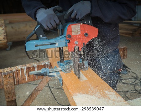 Close-up of the hands of a man with chain mortiser cutting a wooden board