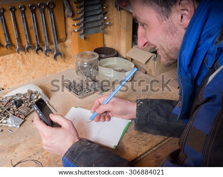 Laughing carpenter with blueprint and smart-phone