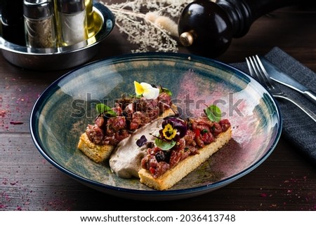two bruschettas with beef tartare on a plate, Crostini with Beef Tartare, beef Bruschetta, sandwich with raw gourmet beef