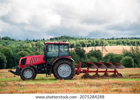 Red Tractor Plowing in Autumn, Farmer in tractor plowing the land in autumn 商業照片 © 