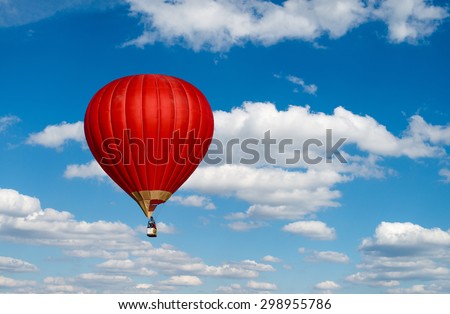Red hot air balloon in blue cloudy sky