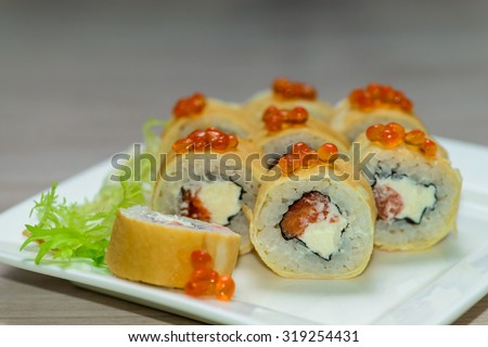 Close-up of a white plate with sushi set - Russian pancakes with caviar and strawberries , horizontal shot