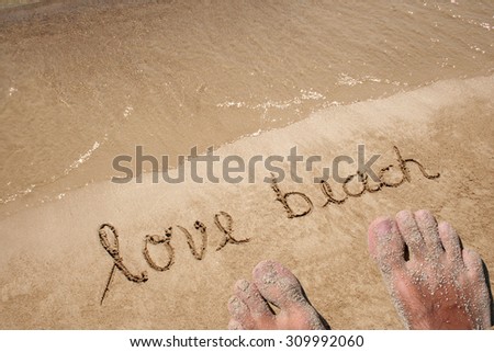 Conceptual hand made or handwritten text in sand on a beach in an exotic island with feet for summer, ocean, sea, travel, vacation, tourism, tropical, coast, message, resort, paradise, sunny or water