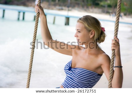 Pretty girl swinging on rope swings on the beach
