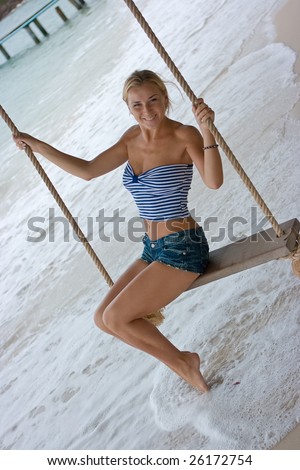 Blond girl on rope swings at the beach