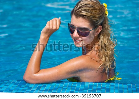 Happy beautiful blonde girl in the water of a hotel swimming pool