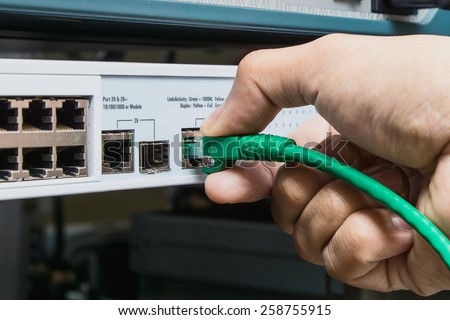 man connecting network cable to switch