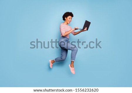 Full length body size side profile photo of pretty cheerful cute nice charming youngster typing before laptop wearing jeans denim striped shirt isolated pastel color blue background