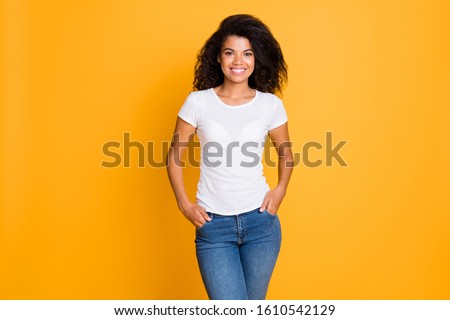 Photo of cheerful positive nice cute girlfriend with hands in pocket standing confidently in white t-shirt isolated over vivid color background in jeans denim 商業照片 © 