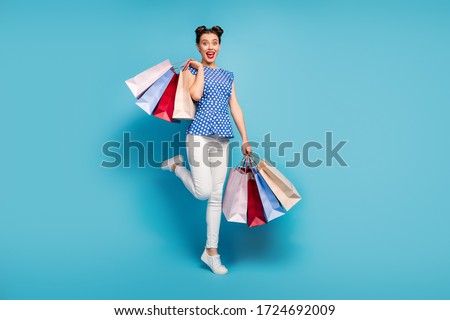 Full length photo of pretty lady carry many packs spree addicted shopaholic rejoicing shopping center wear dotted blouse white pants footwear isolated blue color background Сток-фото © 