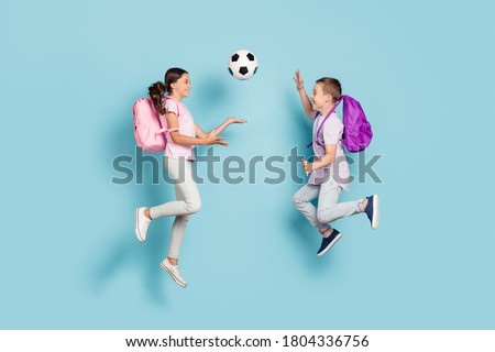 Full length body size view of two attractive small little cheerful friends friendship jumping play soccer cup goal throwing ball hobby leisure isolated blue pastel color background