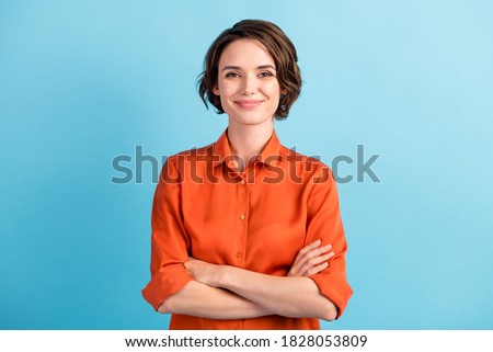 Photo of attractive charming lady cute bobbed hairdo arms crossed self-confident person worker friendly smile good mood wear orange office shirt isolated blue color background