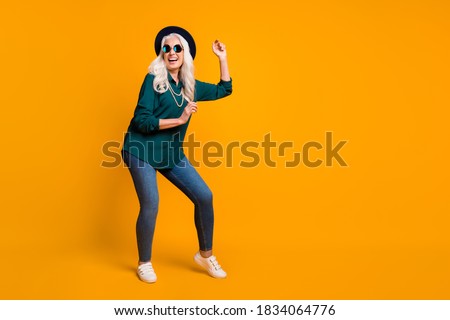 Full body photo of crazy granny lady music lover senior party luxury cool look dance youth moves wear green shirt sun specs necklace retro cap shoes isolated yellow color background