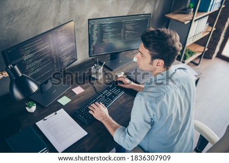 Top above high angle view portrait of his he nice attractive focused skilled geek guy typing bug track report cyberspace security at modern industrial interior style concrete wall work place station