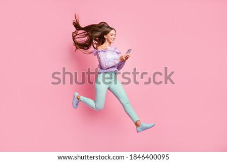 Full length photo of lovely teenager lady dressed casual clothes holding looking modern device isolated pastel pink color background