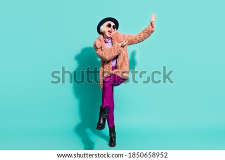 Photo of adorable cute old woman dressed vintage outerwear cap eyewear dancing isolated turquoise color background