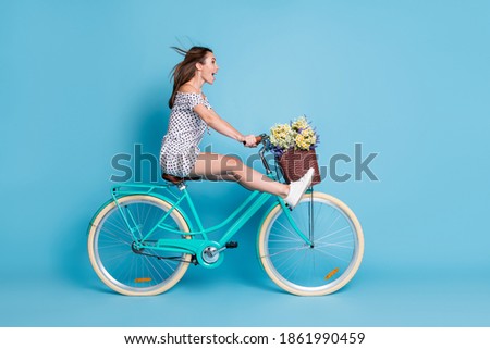 Full length profile photo of crazy girl drive bike raise legs wear dotted short dress footwear isolated blue color background