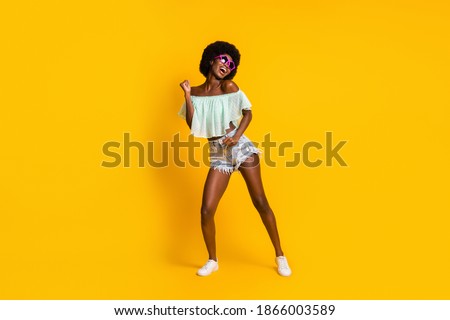Full length body size photo of black skinned woman dancing on weekend wearing star shaped sunglass isolated on vibrant yellow color background