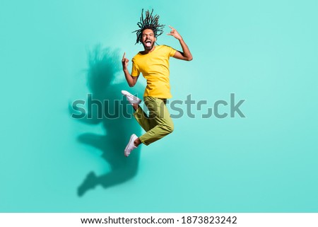 Full size photo of young happy smiling crazy excited afro man jumping show rock n roll sign isolated on turquoise color background Stock fotó © 