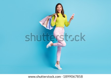Photo portrait full body view of woman standing on one leg holding phone shopping bags isolated on pastel blue colored background Foto stock © 