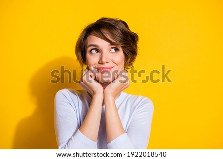 Photo of adorable positive lady look empty space hands cheeks wear white shirt isolated yellow color background