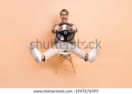 Full size photo of happy excited crazy attractive man in glasses riding car fast extreme isolated on beige color background