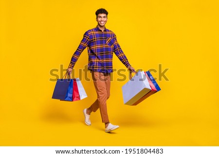 Full body photo of young cheerful afro man happy positive smile go walk step shopping bags isolated over yellow color background Сток-фото © 