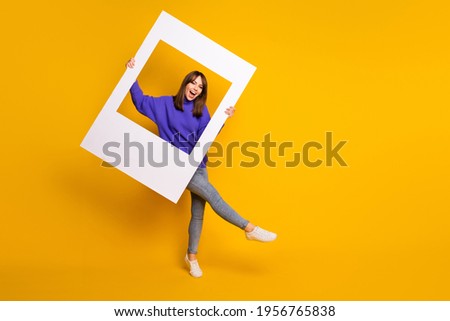 Photo of adorable charming young woman wear purple sweater dancing holding white photo frame isolated orange color background