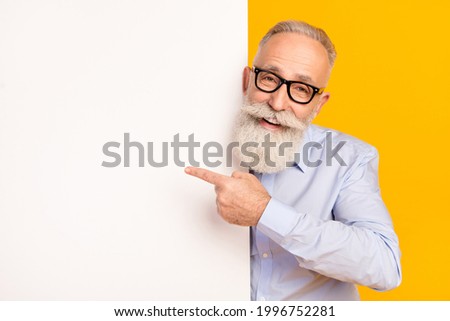Photo of retired old man retired businessman point finger empty space banner wear glasses isolated on yellow color background