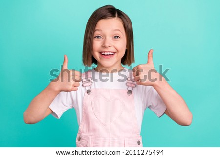 Photo of cheerful happy young small girl make fingers thumbs up smile recommend isolated on teal color background 商業照片 © 