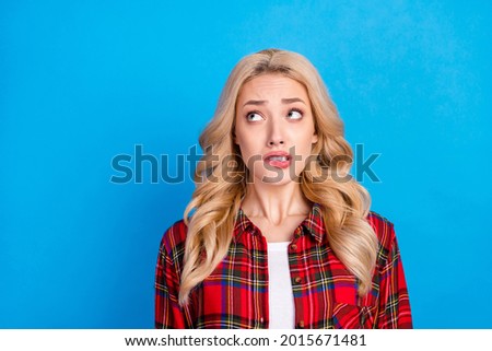 Photo of nervous blond hairdo young lady bite lip look up wear red shirt isolated on blue color background Foto d'archivio © 
