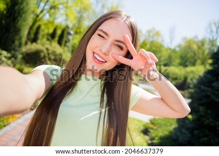 Photo of funny sweet woman dressed green outfit recording video v-sign cover eye smiling outside urban city street Stock fotó © 