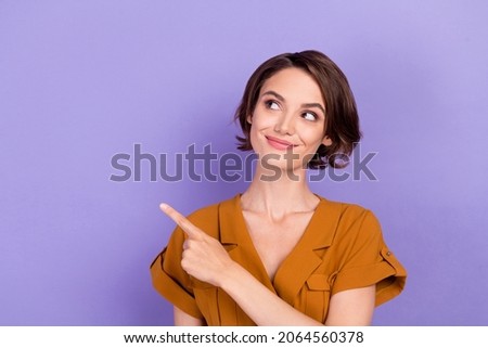 Photo of young woman happy positive smile look indicate finger empty space recommend sale isolated over violet color background Foto d'archivio © 