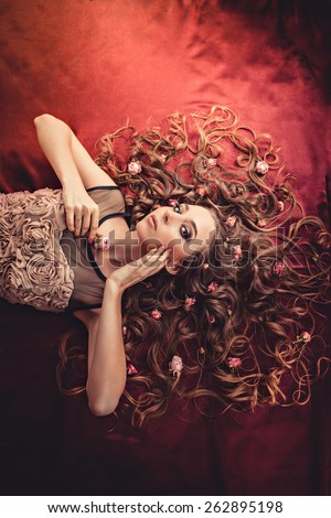 hair with roses expand on the fabric colored Marsala. top view image of a girl with long curly hair.