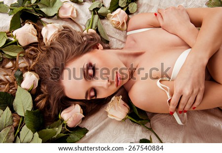 girl with roses.  image top view of a girl who is lying in lingerie on the bed with roses