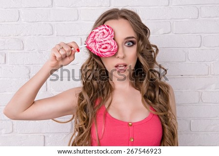 pretty girl closed her eyes candy. beautiful girl licking a pink lollipop. girl has a very long hair
