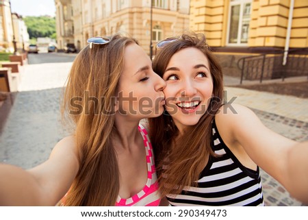 Friends making selfie. Two beautiful young women making  selfie and kissing