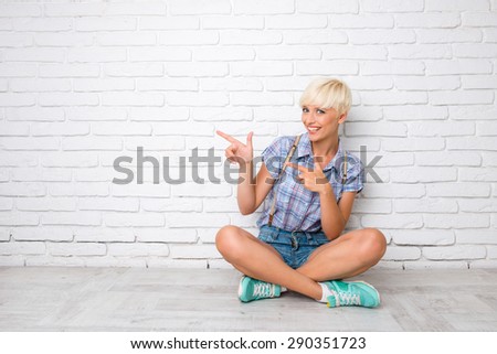 Happy young girl in casual shirt pointing away