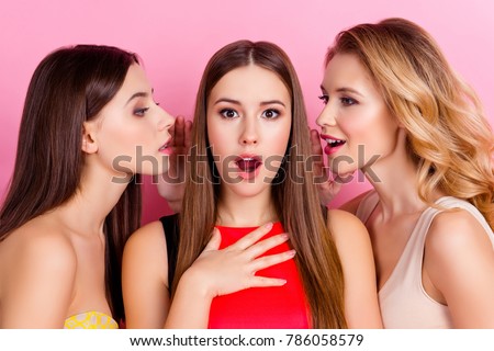 Close up of two charming girls holding hand near mouth telling gossips on ears to their shocked friend with open mouth who giving impressed, unexpected reaction while standing over pink background Stock foto © 