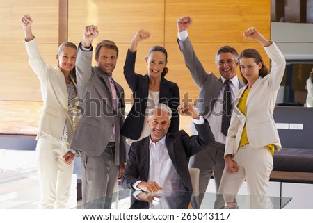 Business team of six smiling executives rising fist in the air.