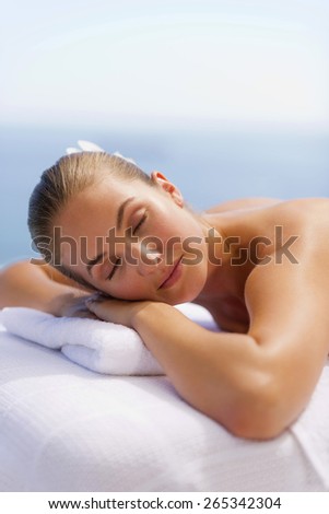 Portrait of young woman bare cheated lying on a massage table, with eyes closed.