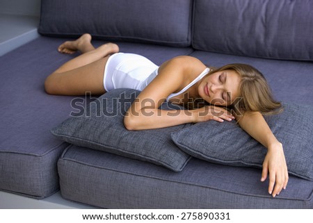 Young blond woman lying down on blue sofa.
