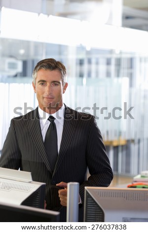 Business executive dressed in black standing in open space office.