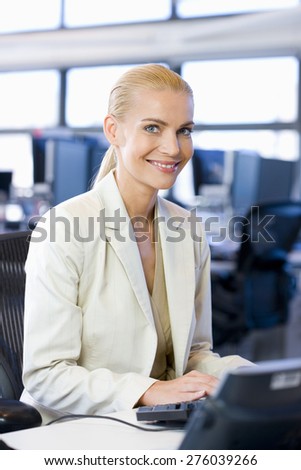Smiling blond female business executive using computer.