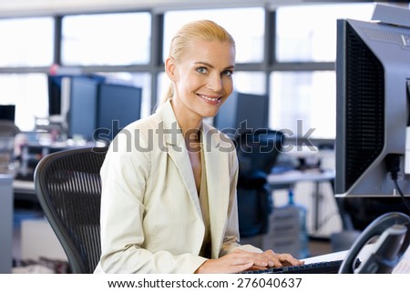 Smiling blond female business executive using computer.