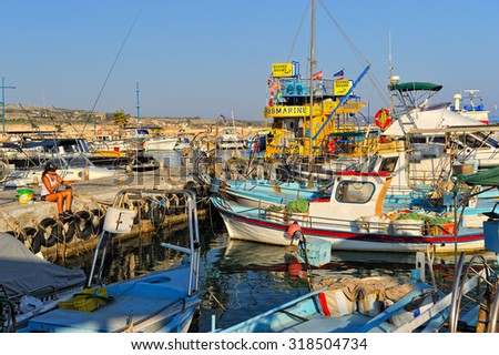 Ayia Napa, Cyprus - 3 September, 2015: Girl fishing among fishing boats in the fishing bay of Ayia Napa