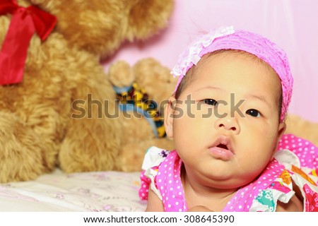 Asian baby poses on pink background and have teddy bear is friends.