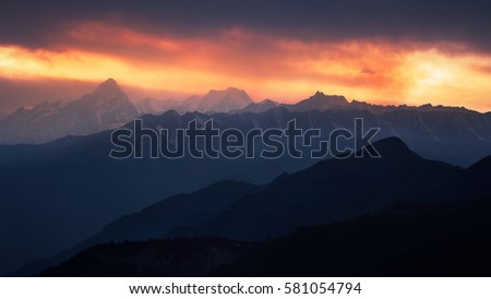 In the cattle Hill halfway up the mountain to see sunset, the sun red clouds, snow capped mountains rolling Stock fotó © 