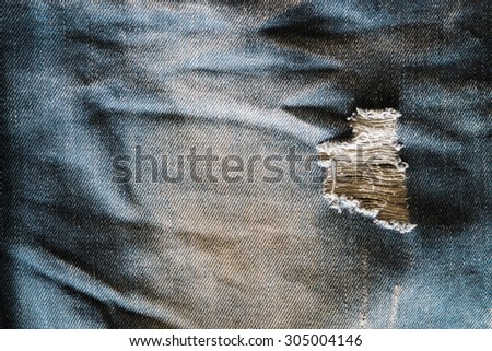 Denim fabrics lacking, blue faded ripped jeans closeup